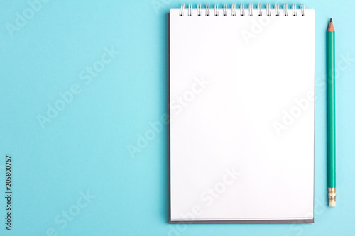 Blank notebook with pencil on blue pastel background. Flat lay concept. Copy space