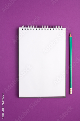 Blank notebook with pencil on purple background. Flat lay concept. Vertical view