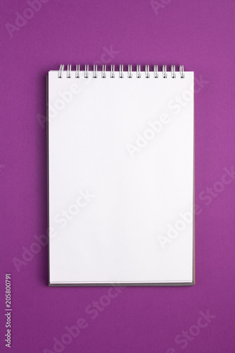 Blank notebook on purple background. Flat lay concept. Vertical view