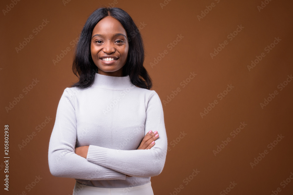 Obraz premium Young beautiful African Zulu businesswoman against brown backgro