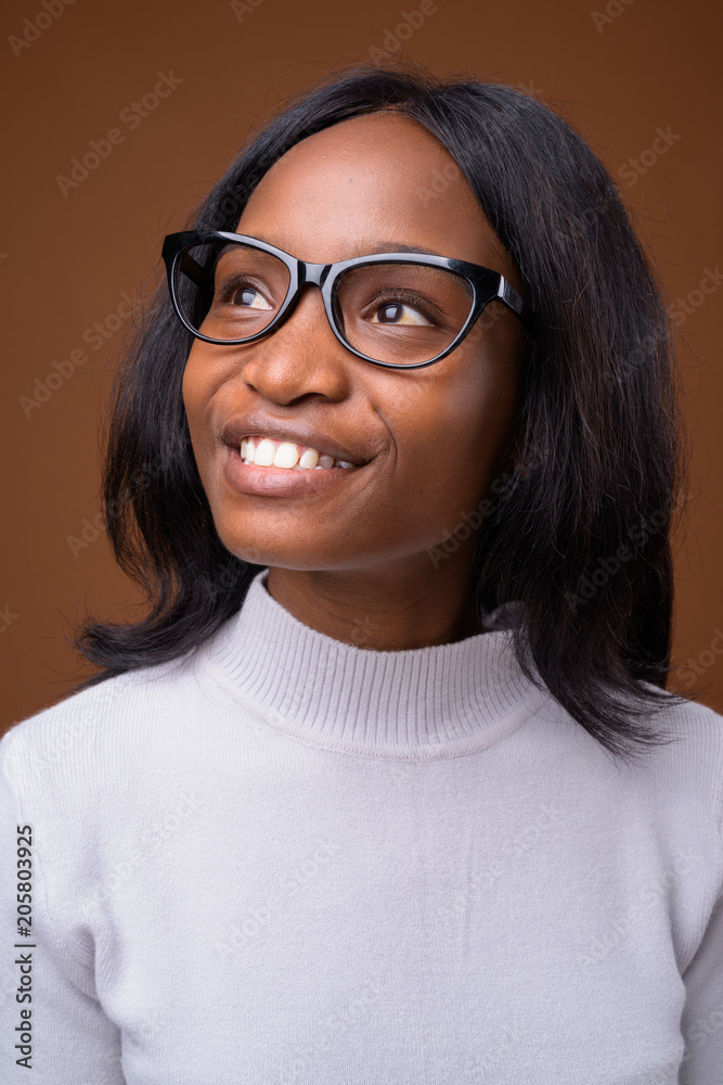 Fototapeta premium Young beautiful African Zulu businesswoman against brown backgro
