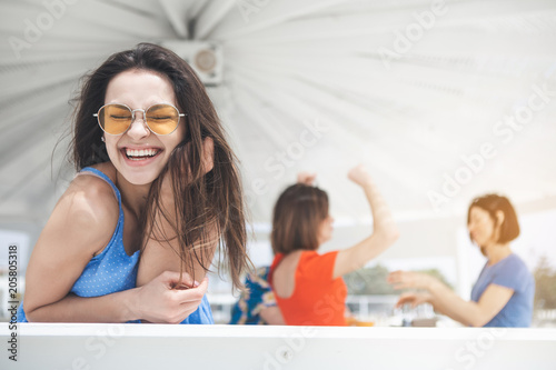 Life is great. Portrait of excited young woman is enjoying summer vacation. She is laughing with relaxation while standing in pavilion. Copy space 