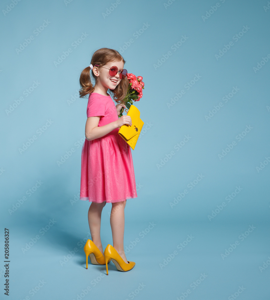 funny child girl fashionista in big mother's shoes on colored background. funny child girl fashionista in big mother's shoes on colored background.