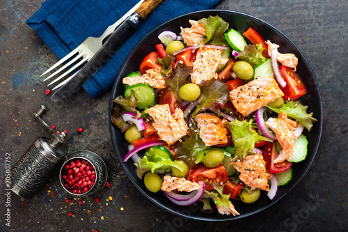 Salad with fish. Fresh vegetable salad with salmon fish fillet. Fish salad with salmon fillet and fresh vegetables on plate