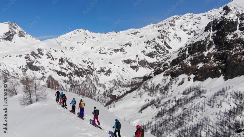 Aerial video. Group of ski touring on skin uphill in a line. Drone shot Ski touring in big mountains, beautiful landscape with high peaks in background. Winter adventure and breath taking view Aerial video. Group of ski touring on skin uphill in a line. Drone shot Ski touring in big mountains, beautiful landscape with high peaks in background. Winter adventure and breath taking view