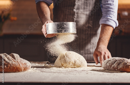 Leinwand Poster Hands of baker kneading dough