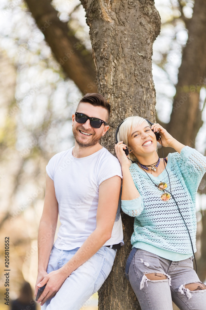 Young students leaning on a tree in campus and smiling Young students leaning on a tree in campus and smiling