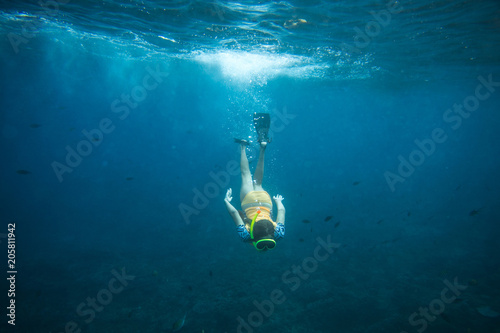 underwater photo of woman in fins, diving mask and snorkel diving alone in ocean