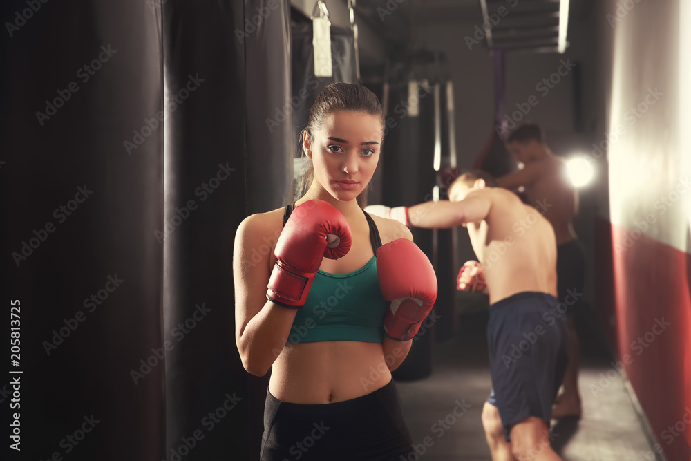 Portrait of young female boxer in gym