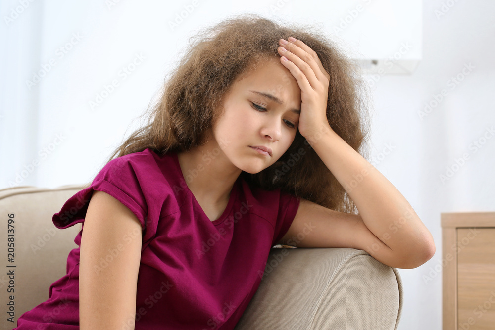 Depressed teenager sitting on sofa in room Depressed teenager sitting on sofa in room