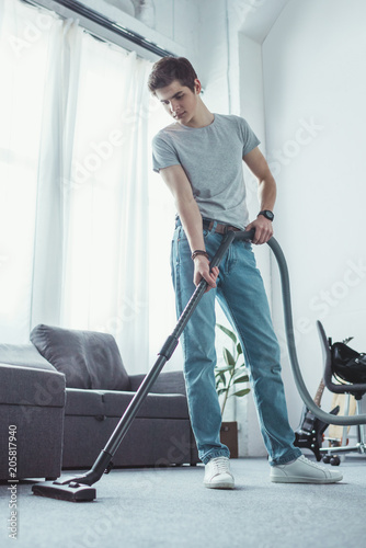 teenager cleaning floor with vacuum cleaner