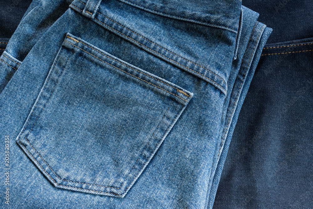 back side of jeans with pocket on dark blue denim background.