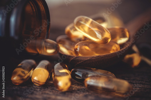 Close up the vitamin D and Omega 3 fish oil capsules supplement on wooden plate for good brain , heart and health eating benefit photo