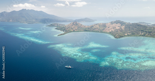 Aerial Panoramic View of Reef and Pinisi Ship Near Flores, Indonesia photo