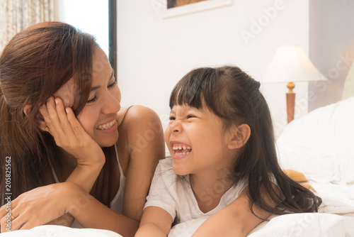 Mother and daughter enjoy in bed at home