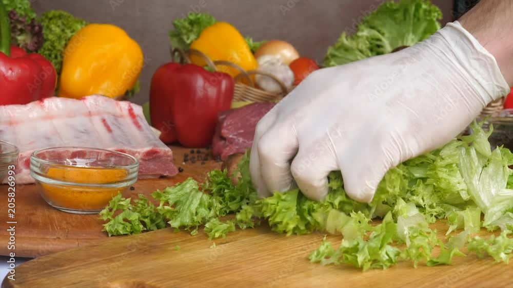 Cutting salad leaves on a wooden board on a wave of raw meat and vegetables Cutting salad leaves on a wooden board on a wave of raw meat and vegetables