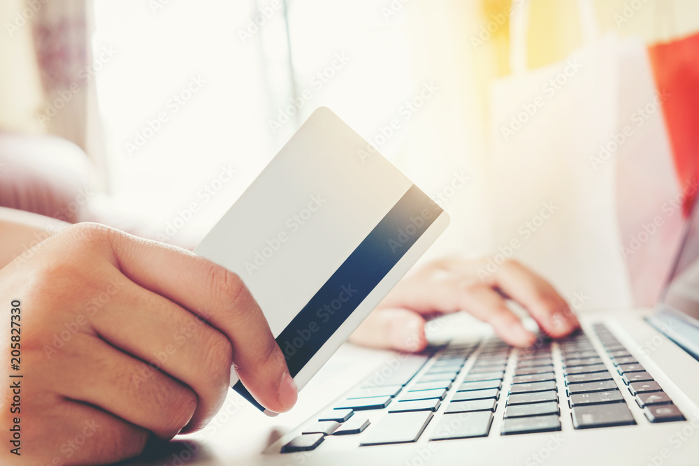 Close up credit card,woman shopping online using laptop enjoying in home Close up credit card,woman shopping online using laptop enjoying in home