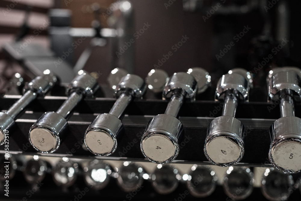 Rows of metal dumbbells for training on rack in modern gym Rows of metal dumbbells for training on rack in modern gym