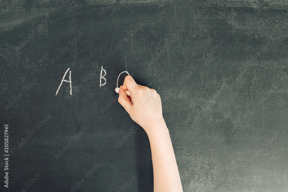 child's hand with chalk write letters a, b, c on black chalkboard, stock photo image