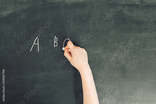 Obraz na płótnie child's hand with chalk write letters a, b, c on black chalkboard, stock photo image w salonie