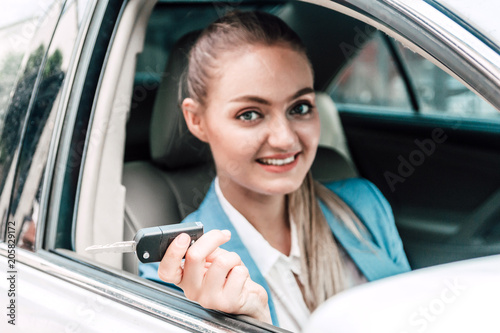 Business woman looking at camera and showing car keys while sitting in car