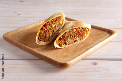 Burritos wraps with meat, beans and vegetables on wood board photo