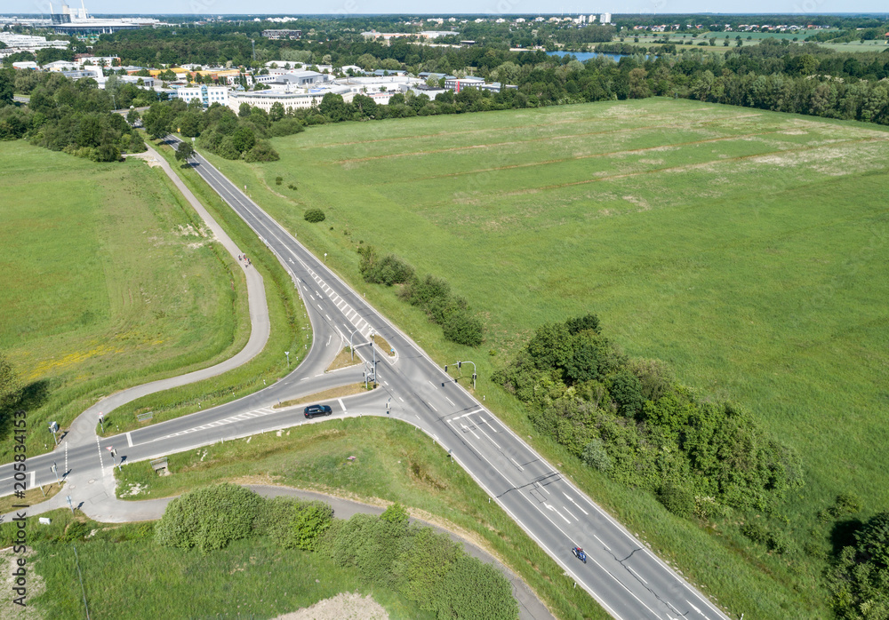 Aerial view of the turn-off of a ring road with the houses of the dominion in the background