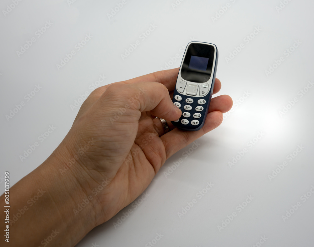 Woman hand holding the world smallest mobile phone with OLED screen in blue plastic body isolated on white Woman hand holding the world smallest mobile phone with OLED screen in blue plastic body isolated on white