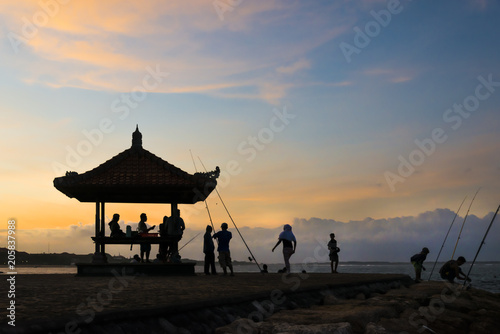 Sunset on the beach, silhouette hut and a few people © Jeff