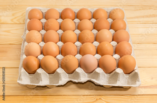 Brown eggs in the cardboard egg tray on wooden surface
