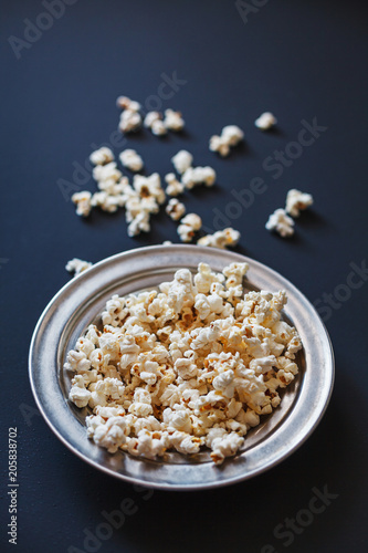 Popcorn in a metallic plate on a dark painted matte surface