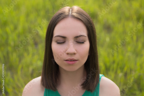 Outdoors portrait of young dark hair woman with closed eyes close-up