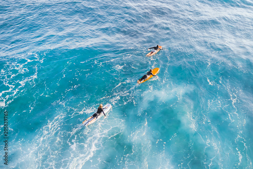 Three surfers in the ocean, top view