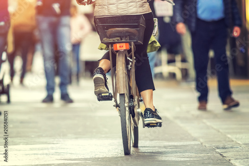 Fototapeta Naklejka Na Ścianę i Meble -  A woman is riding a bike on a city street on a sunny day