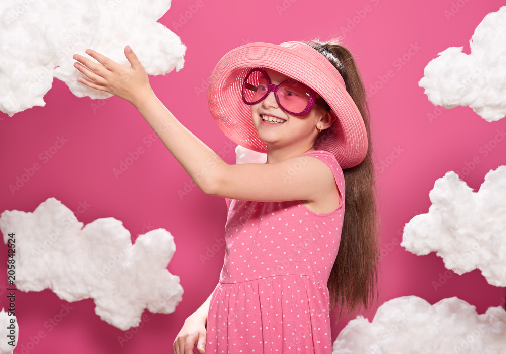 fashionable girl posing on a pink background with clouds, pink dress and hat fashionable girl posing on a pink background with clouds, pink dress and hat