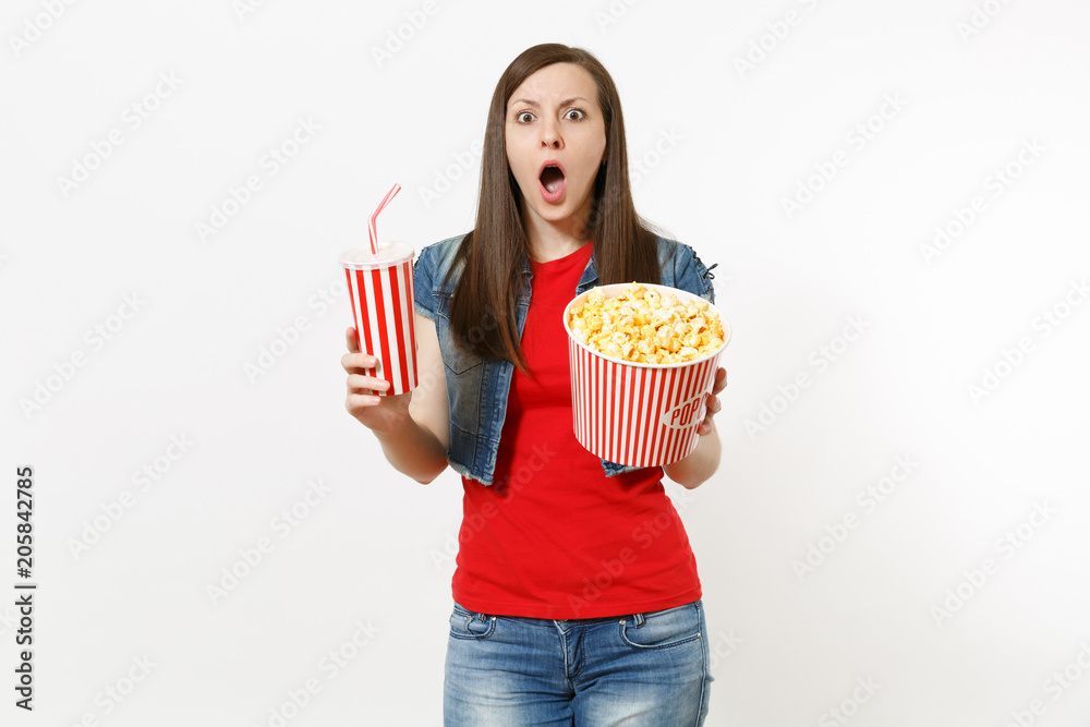 Portrait of young shocked concerned woman in casual clothes watching movie film, holding bucket of popcorn and plastic cup of soda or cola isolated on white background. Emotions in cinema concept.