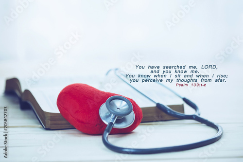 Fototapet stethoscope over the red heart and the open bible  with bible verses from Psalm