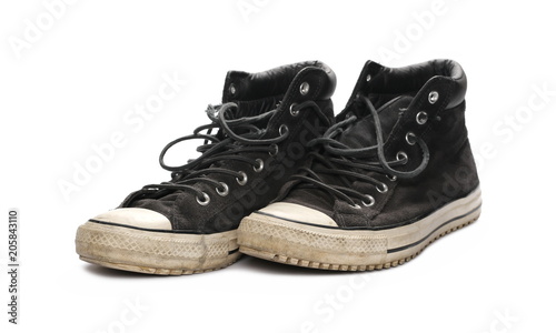 Old black leather sneakers isolated on white background