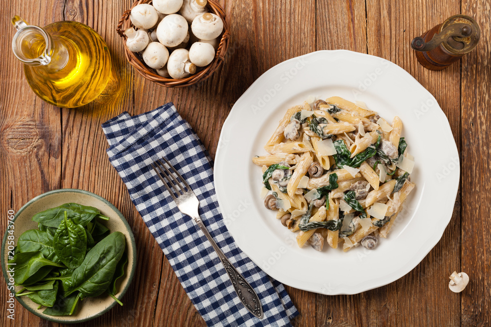 Penne pasta with spinach and mushrooms. Sprinkled with cheese.