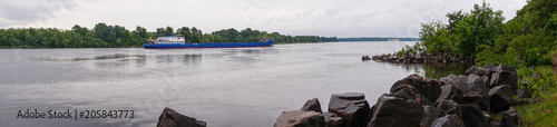 Picturesque spring panorama of the river. Cargo barge and spring rainy day