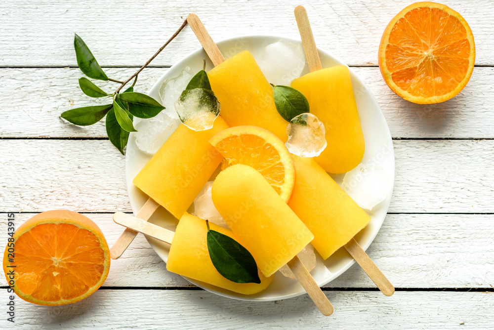 Orange popsicles on white wooden background. Homemade ice pops, top view flat lay Orange popsicles on white wooden background. Homemade ice pops, top view flat lay