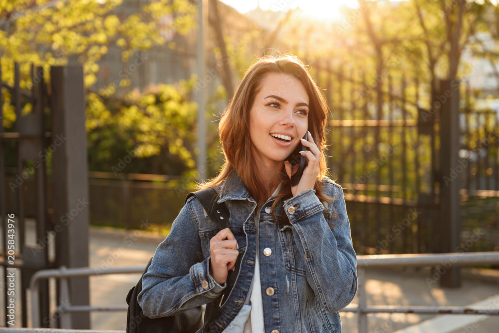 Fototapeta premium Cheerful woman outdoors talking by mobile phone