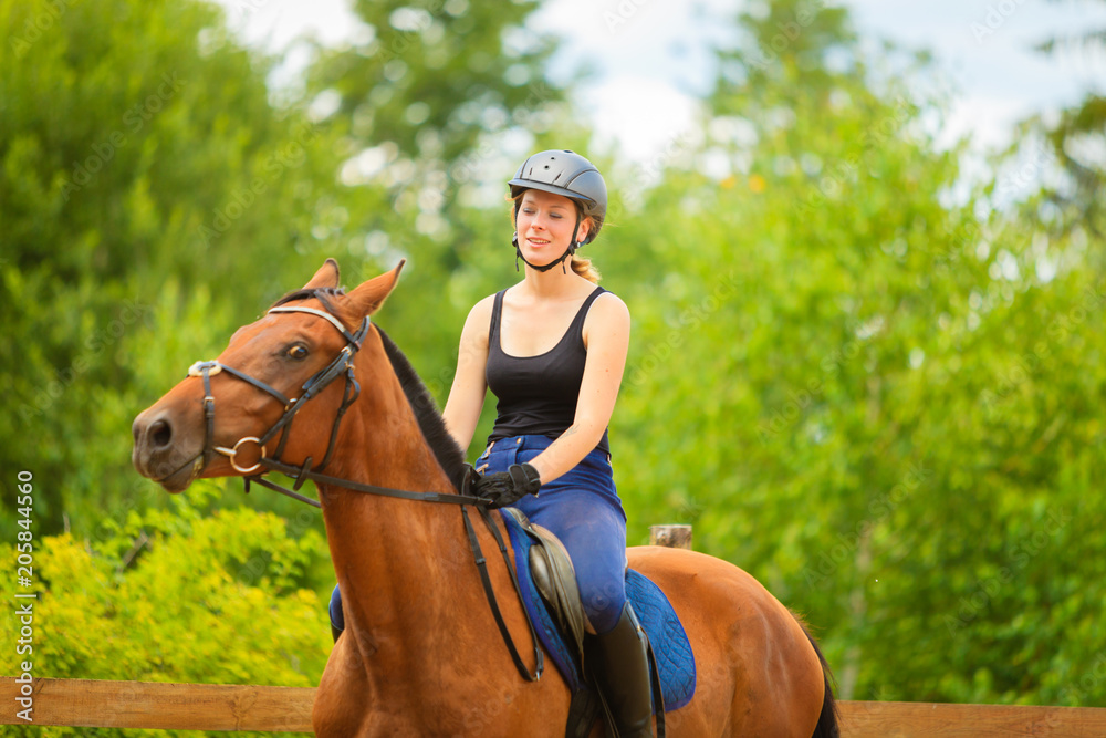 Jockey girl doing horse riding on countryside meadow