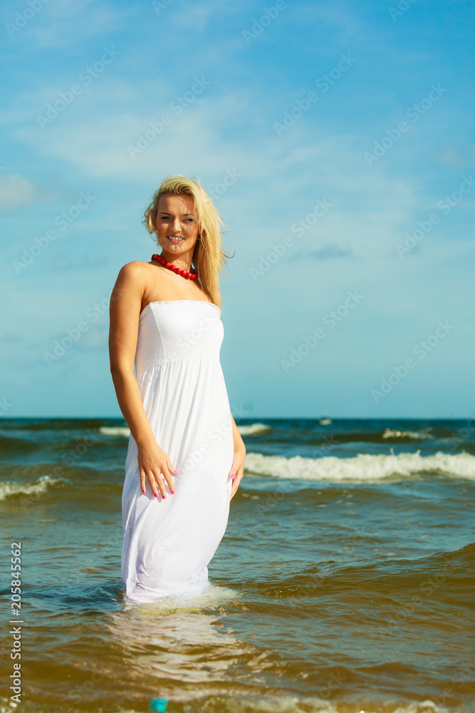 Blonde woman wearing dress walking in water Blonde woman wearing dress walking in water