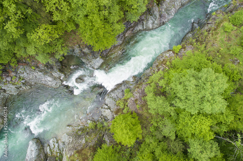 Aerial view of a mountain river flowing between rocks and forests in spring. River Sesia in Valsesia, Piedmont, Italy.