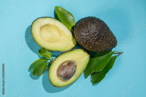 Slices of avocado on bright background. Whole and half with leaves. Design element for product label