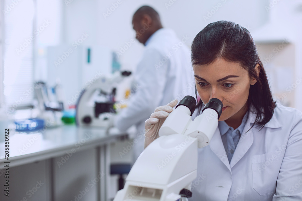 I love biology. Serious professional biologist wearing a uniform and looking into the microscope I love biology. Serious professional biologist wearing a uniform and looking into the microscope