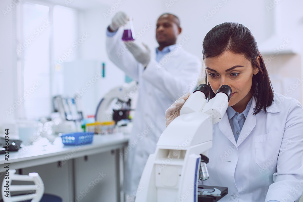My workplace. Determined professional biologist wearing a uniform and looking into the microscope My workplace. Determined professional biologist wearing a uniform and looking into the microscope