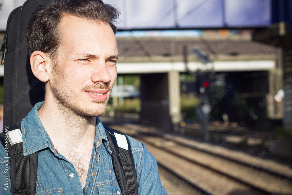 A squinting young man waiting for train on platform, running out of patience, in London A squinting young man waiting for train on platform, running out of patience, in London