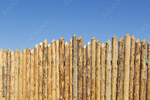 Wooden fence made of sharpened planed logs.